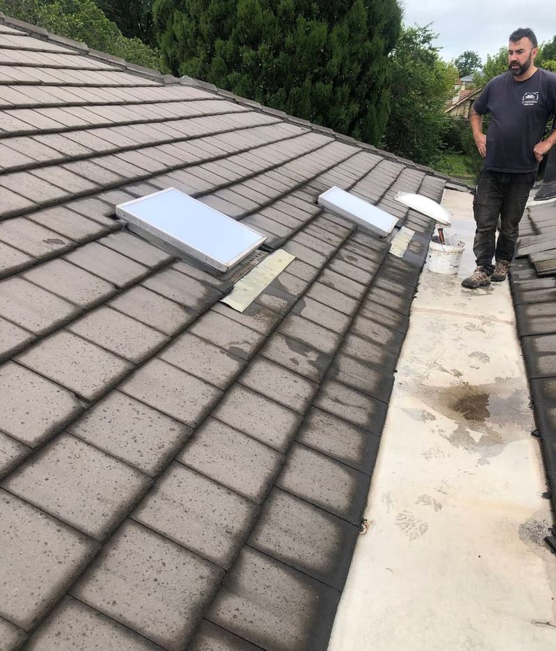 Roofer inspecting two skylights on tile roof